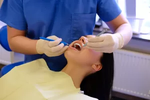 A dentist working on a young woman patient with dental tools at the Ridge Oral Surgery clinic.