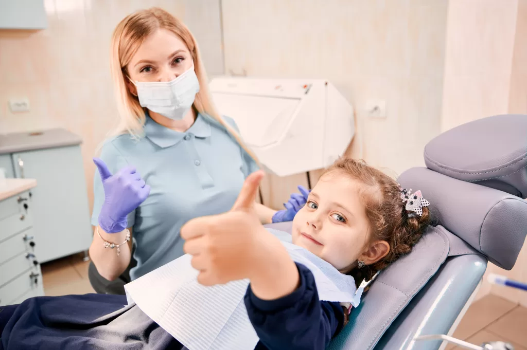 A dentist and a girl showing thumbs up at the Ridge Oral Surgery clinic.