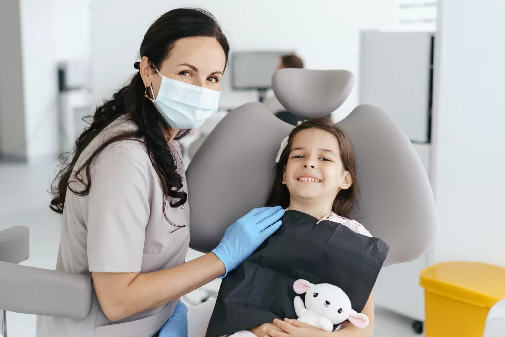A girl smiling at the dentist during her back-to-school checkup at Ridge Oral Surgery clinic.