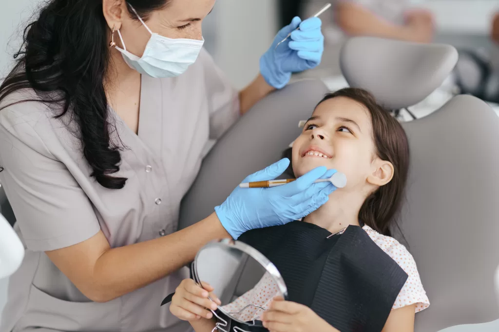 A girl smiling at the dentist during her back-to-school checkup at Ridge Oral Surgery clinic.