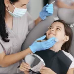 A girl smiling at the dentist during her back-to-school checkup at Ridge Oral Surgery clinic.