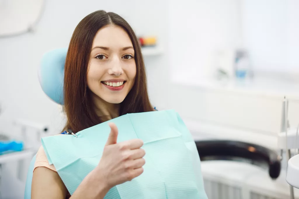 A girl at the Ridge Oral Surgery clinic smiles and shows a thumbs up.