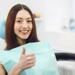 A girl at the Ridge Oral Surgery clinic smiles and shows a thumbs up.