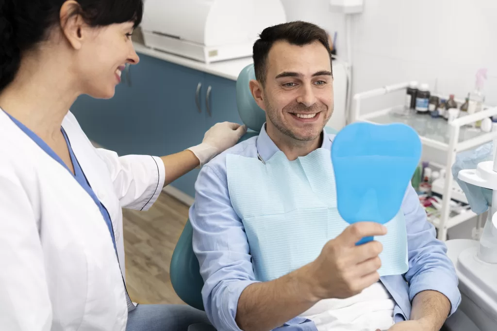 Dentist examining a patient’s dental implant while the patient checks in a mirror during a follow-up visit at Ridge Oral Surgery.