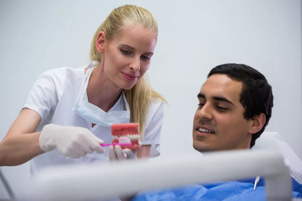 Dentist showing a model of teeth to a patient at Ridge Oral Surgery while discussing implant risks and treatment planning.