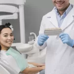 Dentist presenting a tooth shade guide to a smiling patient at Ridge Oral Surgery to plan a natural-looking dental implant restoration.