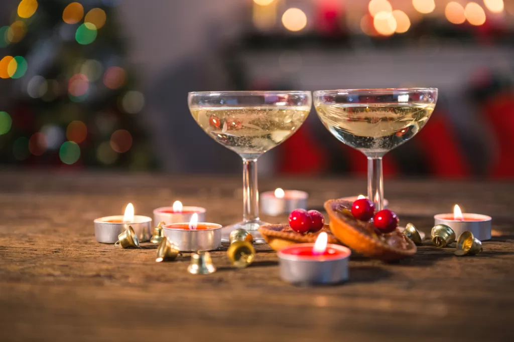 Champagne glasses placed on a festive table with candles and holiday decor.