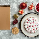 Christmas desserts and festive treats displayed on a table, with a cake, cranberries, and presents.