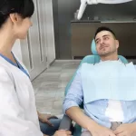 Patient seated in a dental chair discussing wisdom teeth removal and surgical planning with a dental professional at Ridge Oral Surgery.