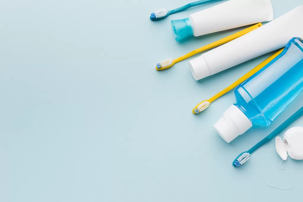 Minimalist flat lay of toothbrushes, floss, and oral care essentials on a blue background representing a simple New Year dental routine.