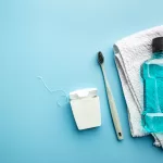 Oral care essentials including a toothbrush, towel, and mouthwash arranged on a blue background.