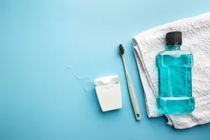 Oral care essentials including a toothbrush, towel, and mouthwash arranged on a blue background.