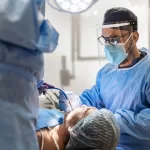 Oral surgeon performing a precise dental surgical procedure using advanced instruments in a modern clinic setting.