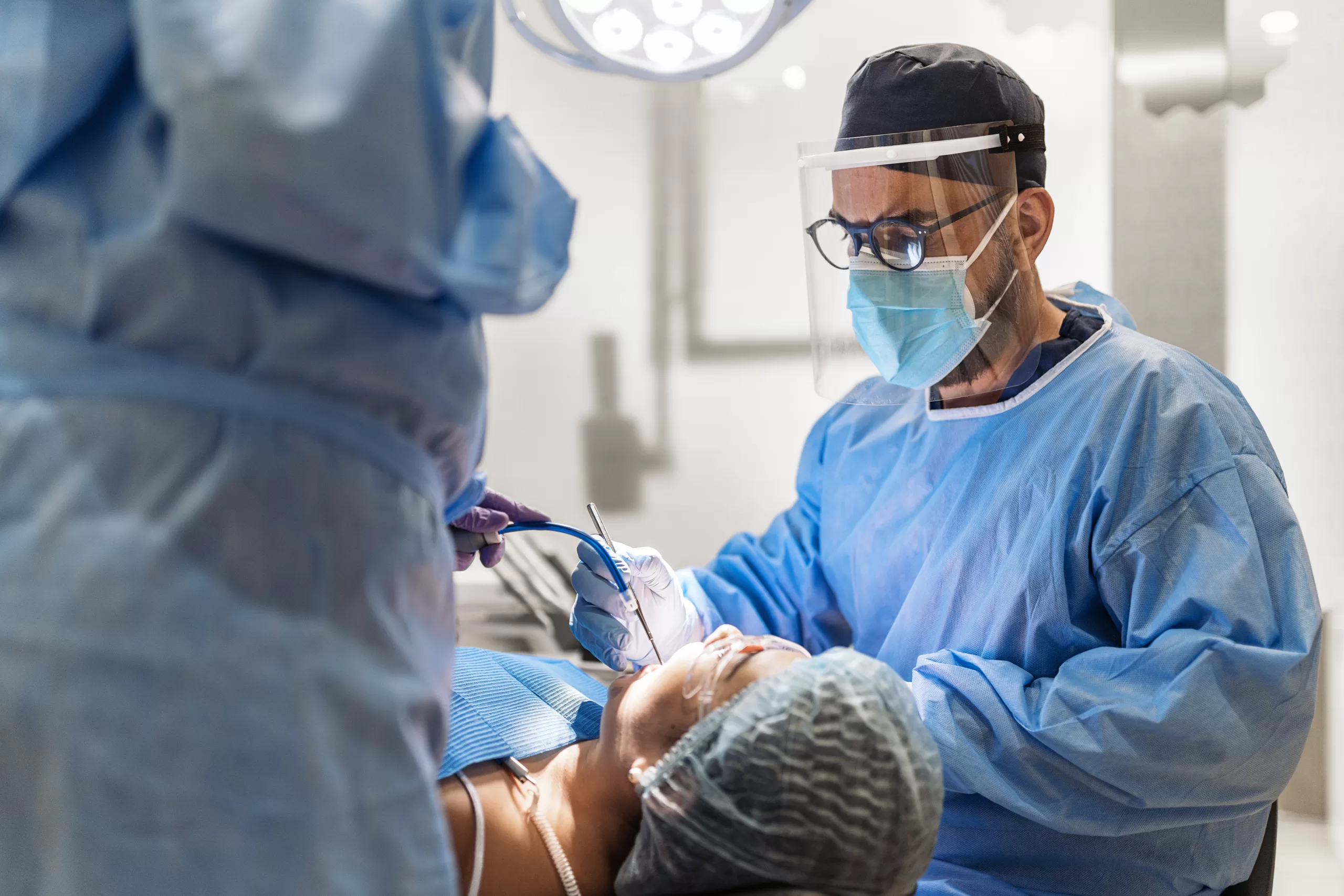 Oral surgeon performing a precise dental surgical procedure using advanced instruments in a modern clinic setting.