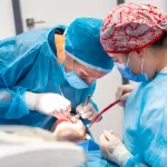 Dental surgeon performing a tooth extraction during a clinical procedure, illustrating professional oral surgery care.