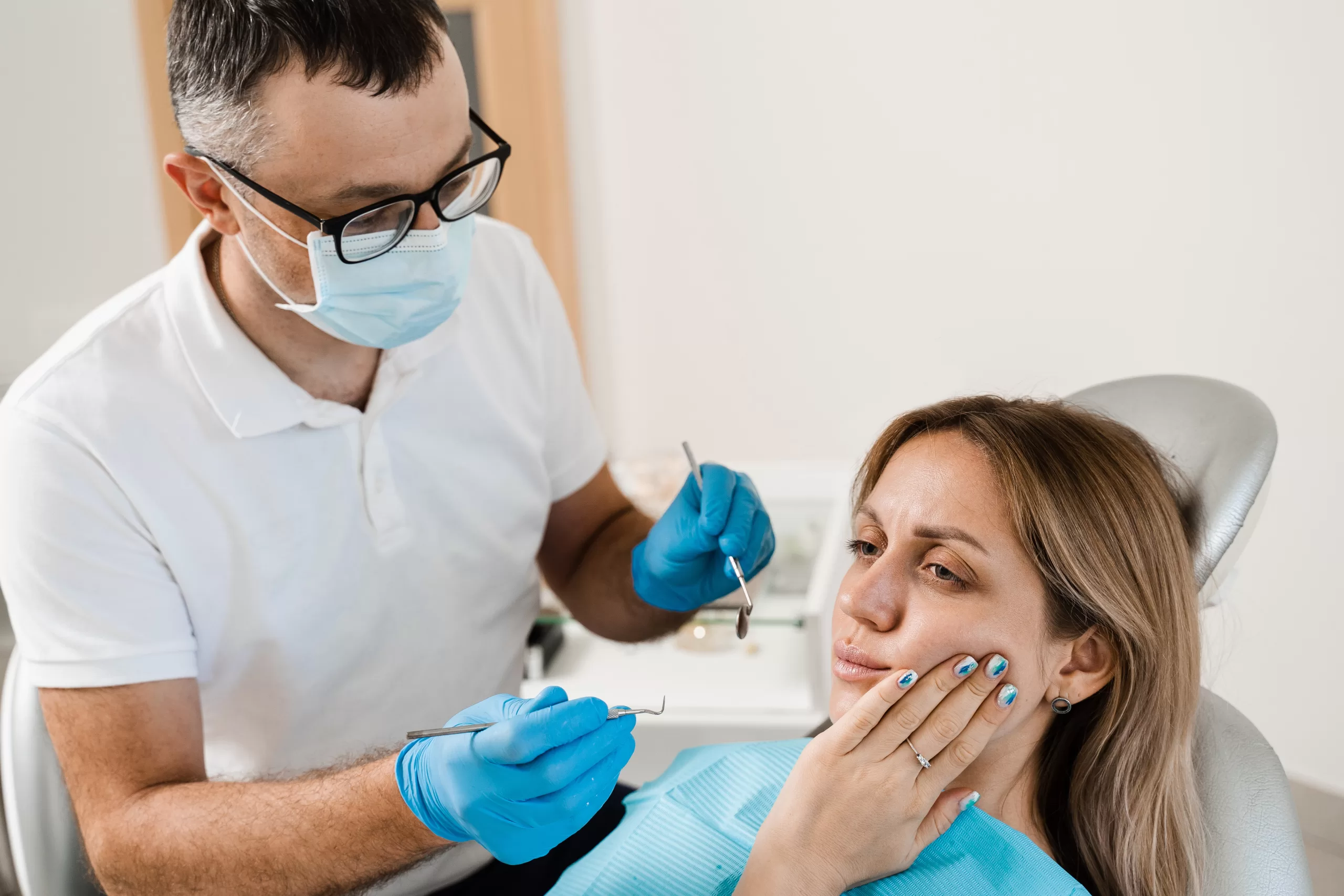 Patient holding jaw due to jaw pain, being checked by a dental professional at Ridge Oral Surgery.