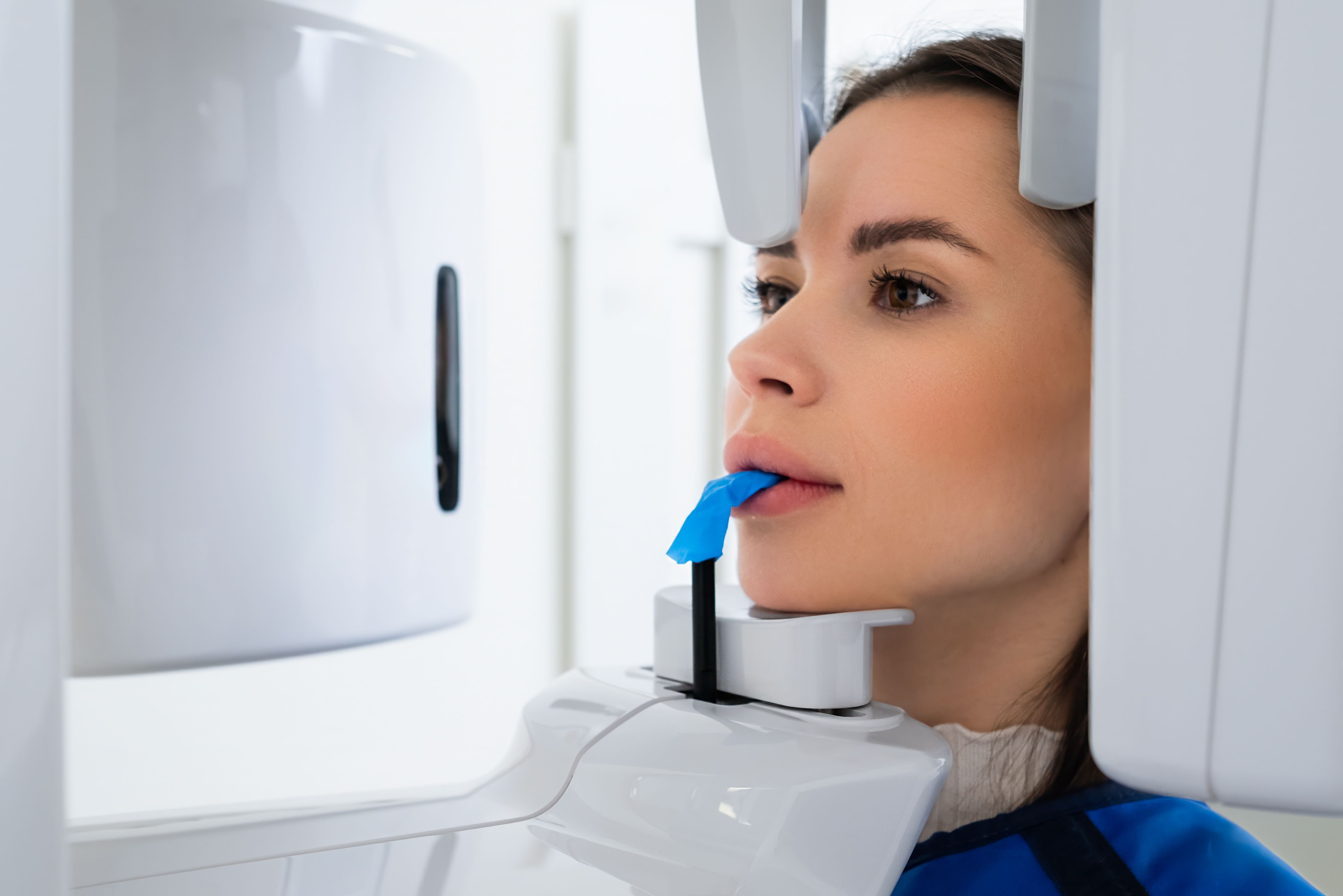 Patient undergoing a panoramic digital dental X-ray scan at an oral surgery clinic.