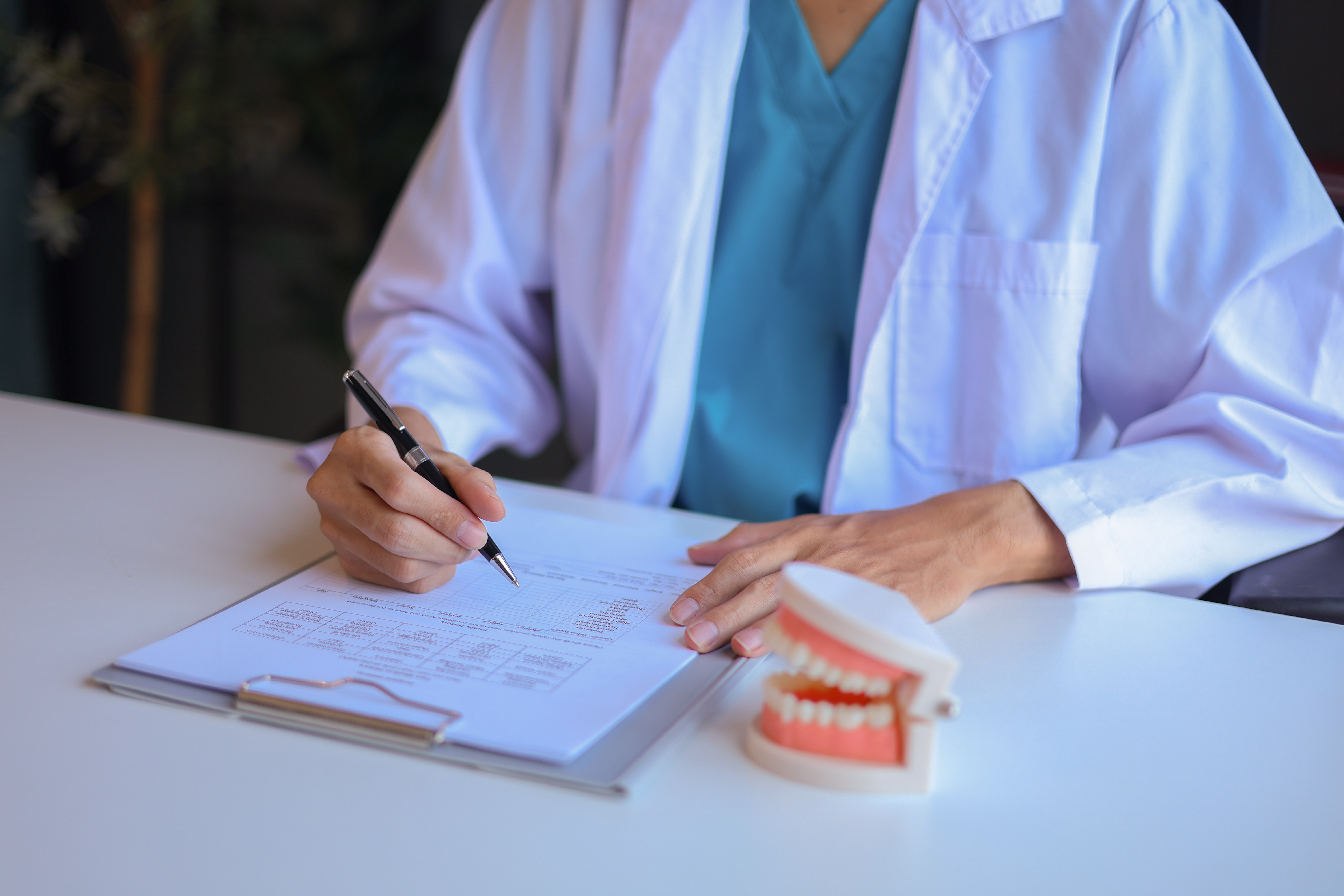Dentist reviewing treatment notes and a dental model while preparing a personalized oral surgery plan at Ridge Oral Surgery.