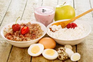 Recovery-friendly foods after wisdom teeth removal, including a yogurt smoothie, eggs, cottage cheese, fresh fruit, and oatmeal arranged on a table.