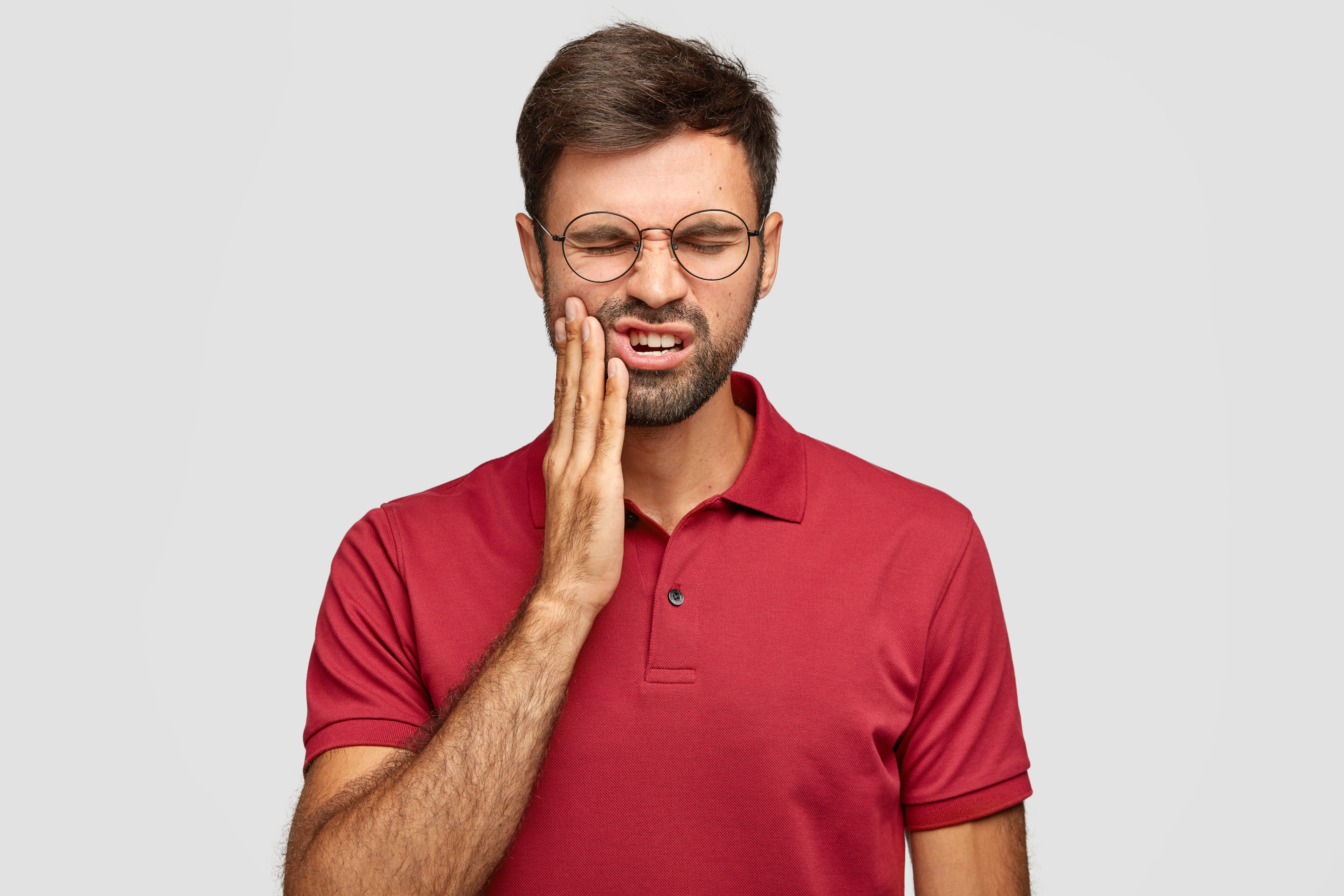 Man holding his jaw in pain, showing symptoms of severe toothache that may require an emergency dental evaluation.