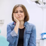 Woman experiencing severe toothache, ready to be treated in Ridge Oral Surgery Clinic.