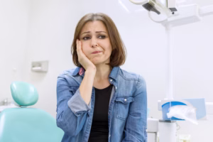 Woman experiencing severe toothache, ready to be treated in Ridge Oral Surgery Clinic.