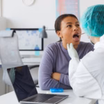 An oral surgeon examines a patient’s mouth for signs of an oral lesion during a biopsy evaluation.