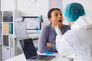 An oral surgeon examines a patient’s mouth for signs of an oral lesion during a biopsy evaluation.